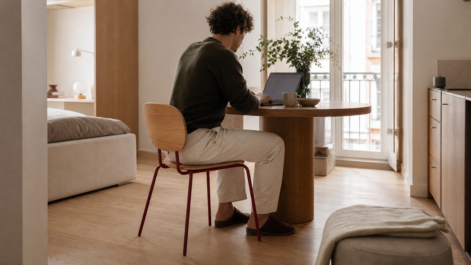 Compact apartment where a natural veneer plywood chair serves dining and laptop work at one table.