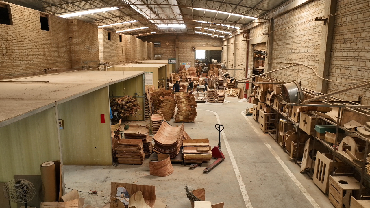 Real DALI Wood factory workshop with bent plywood chair shells and production equipment.