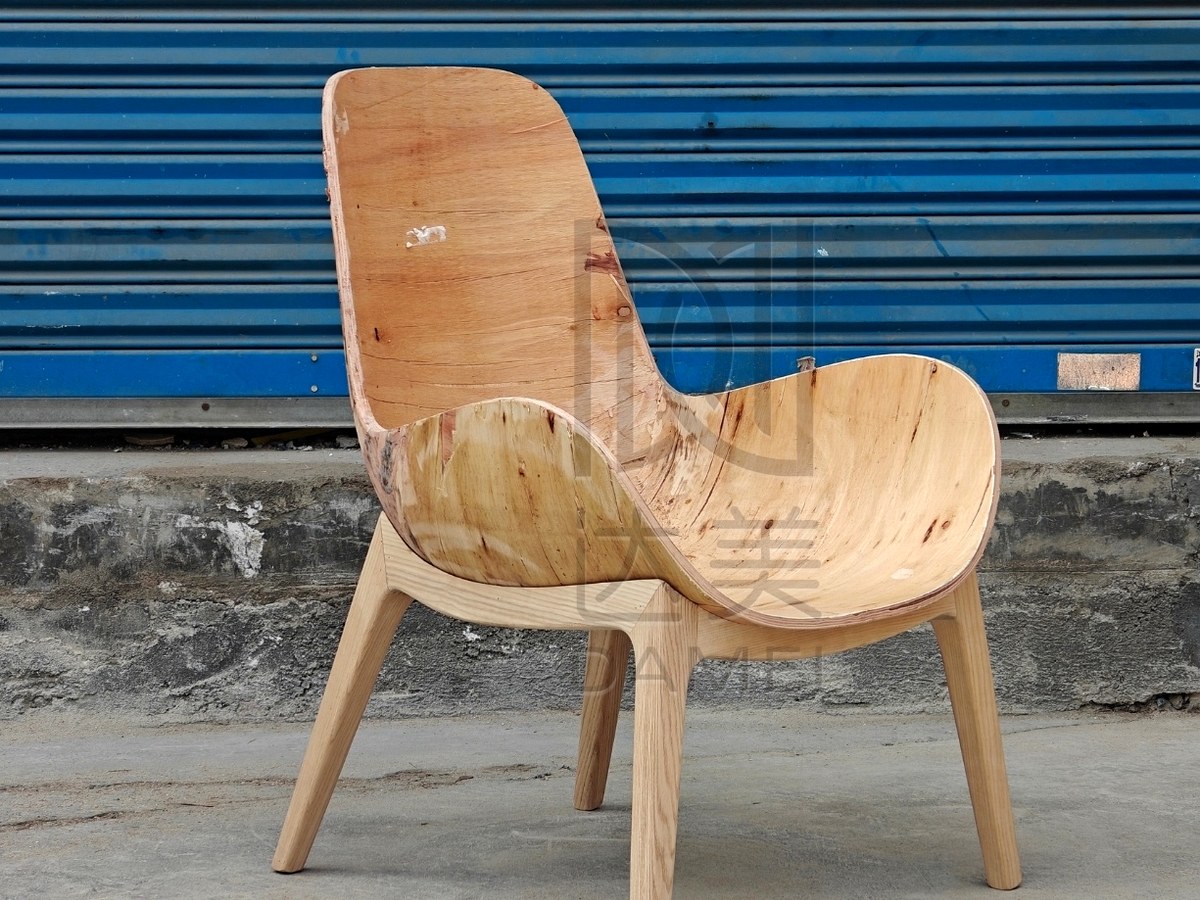 Custom curved plywood lounge chair shell with natural wood grain and solid wood frame.