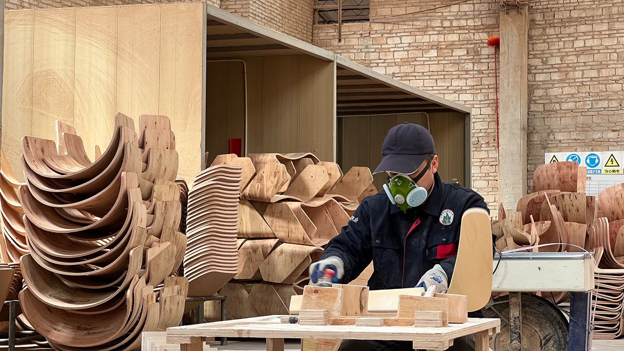 Real DALI Wood worker finishing curved plywood chair components in the factory.