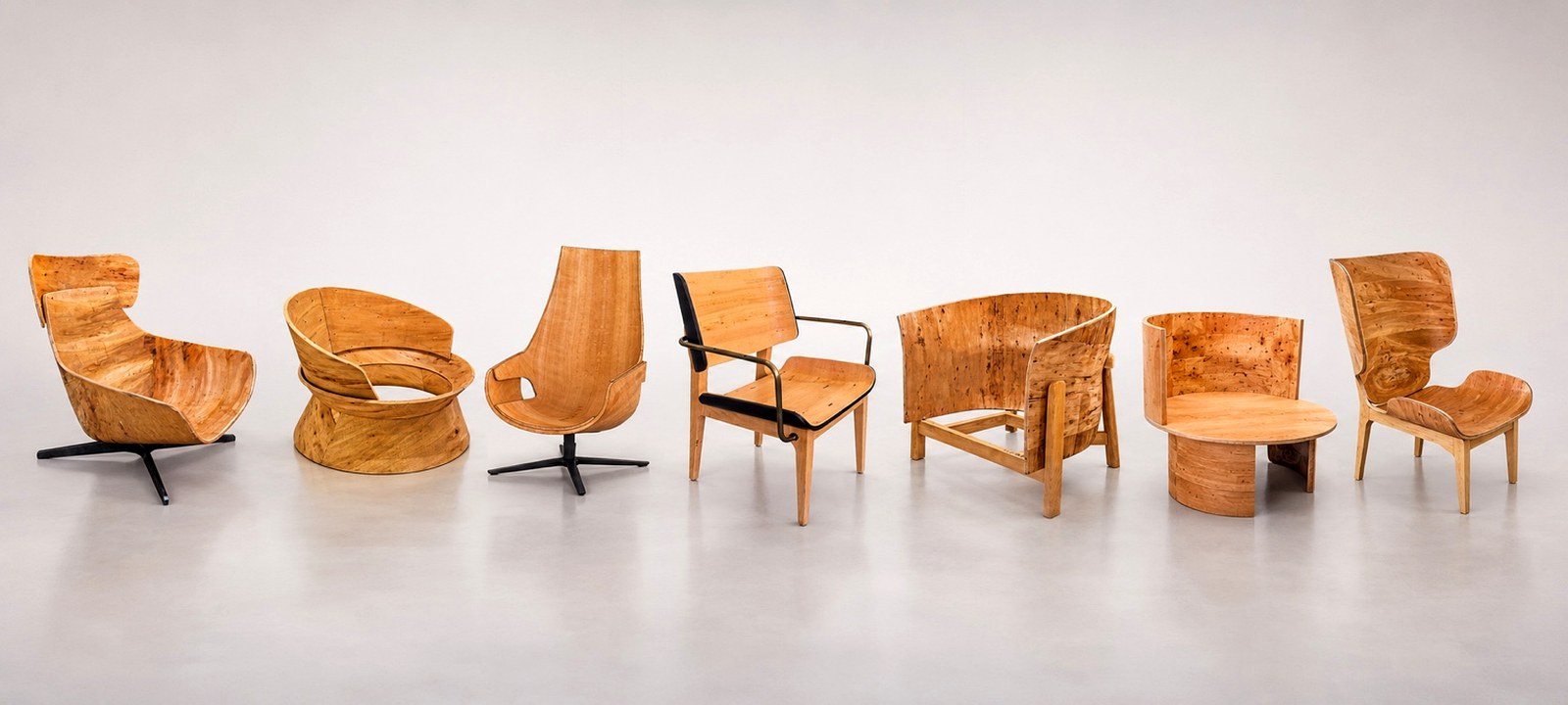 Bent plywood lounge chair and dining chair shell collection with natural wood grain.